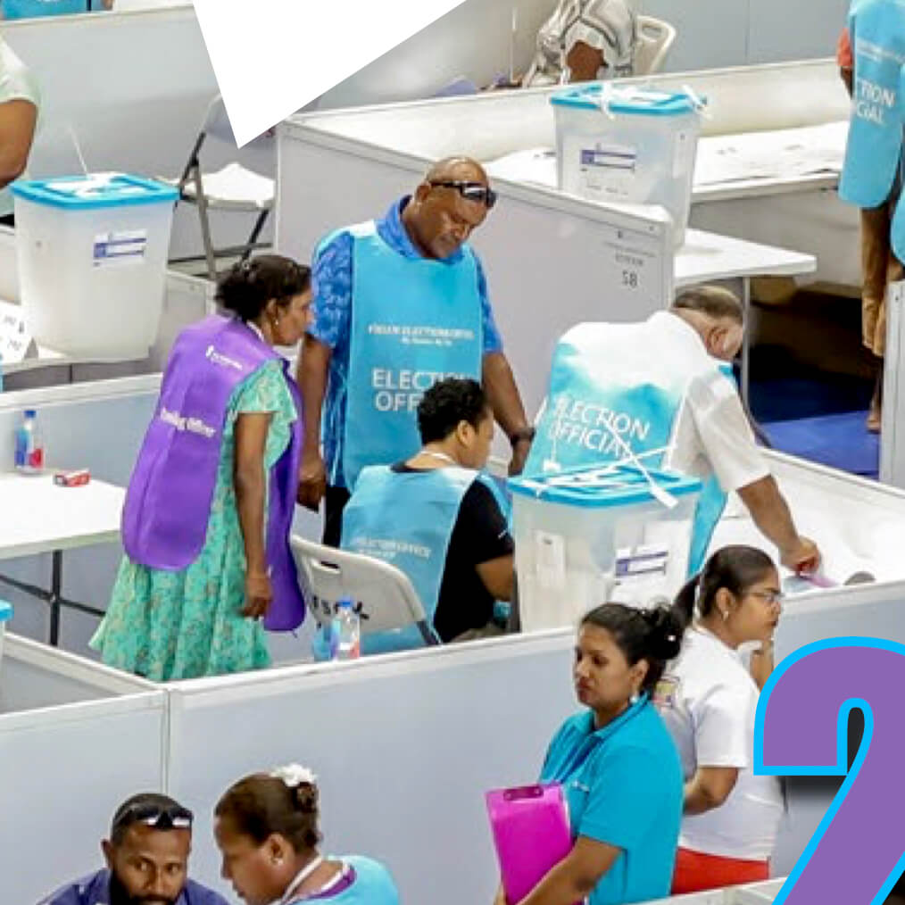 Election officers wearing purple and blue vests at voting booth in Fiji