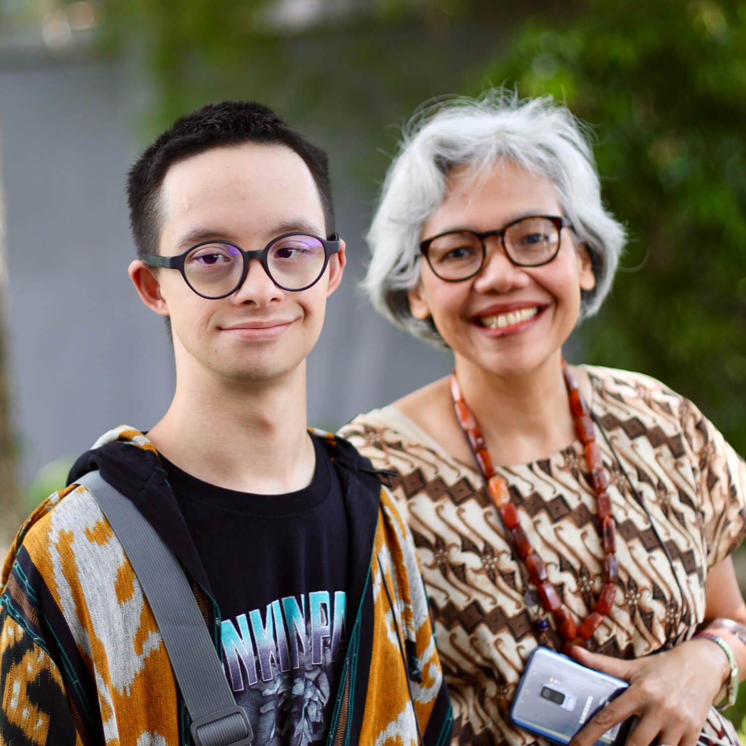 Photo of two Indonesian disability rights activists, a mother-son duo. They are both wearing glasses and smiling.