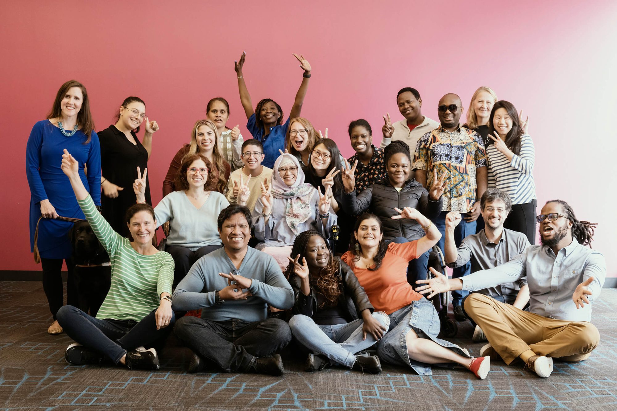 A group photo of DRF staff members smiling and making peace signs and the power sign at the Boston staff retreat.