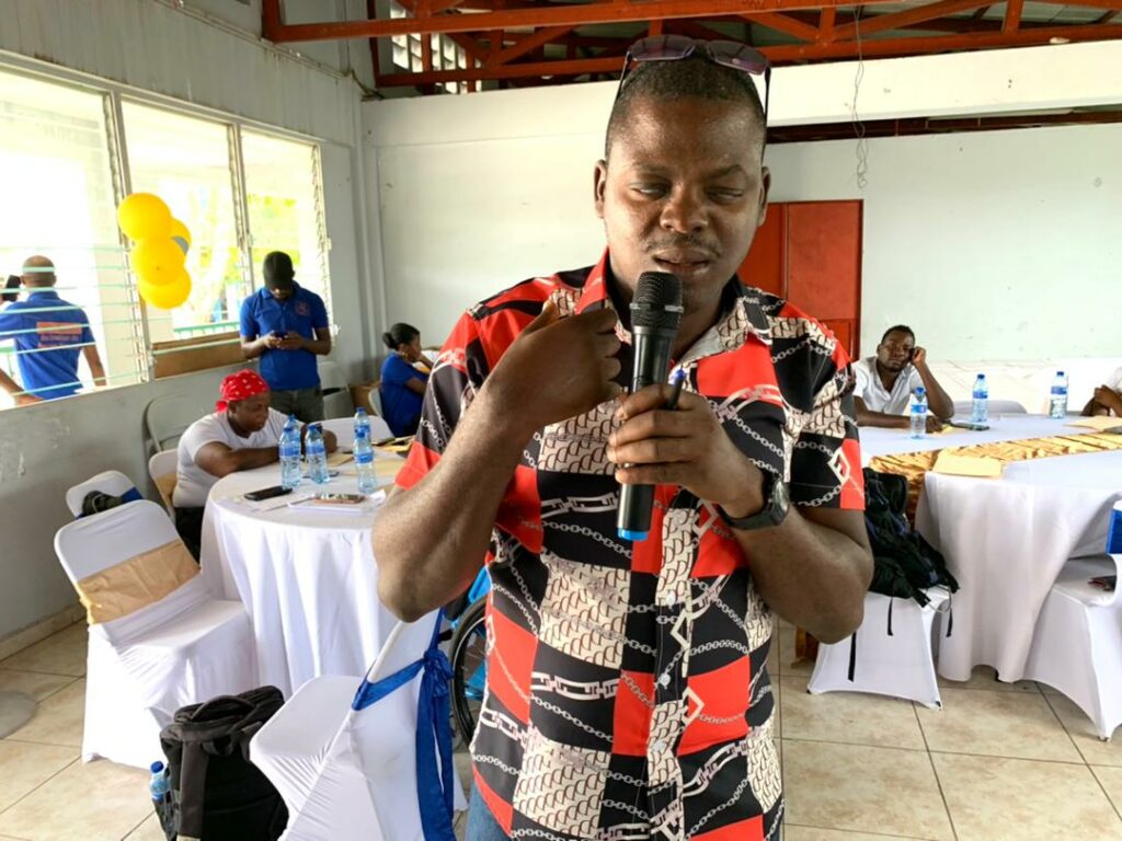 A man wearing a bright colored shirt speaking in a microphone