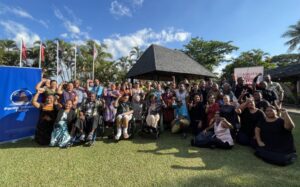 A group photo outdoors on a lawn of the Pacific convening in Nadi, Fiji. Convening participants are raising their fists and smiling.