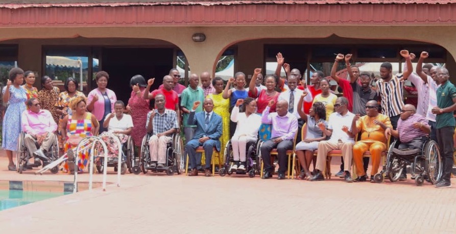 An outdoors group photo of DRF and FEDOMA's grantee convening with DRF grantees and team raising their fists.