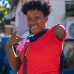 Side shot of Nancy, a Haitian woman wearing a red jersey shirt.