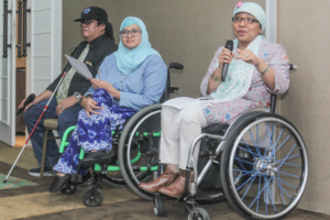 Lady in wheelchair speaking into microphone. 