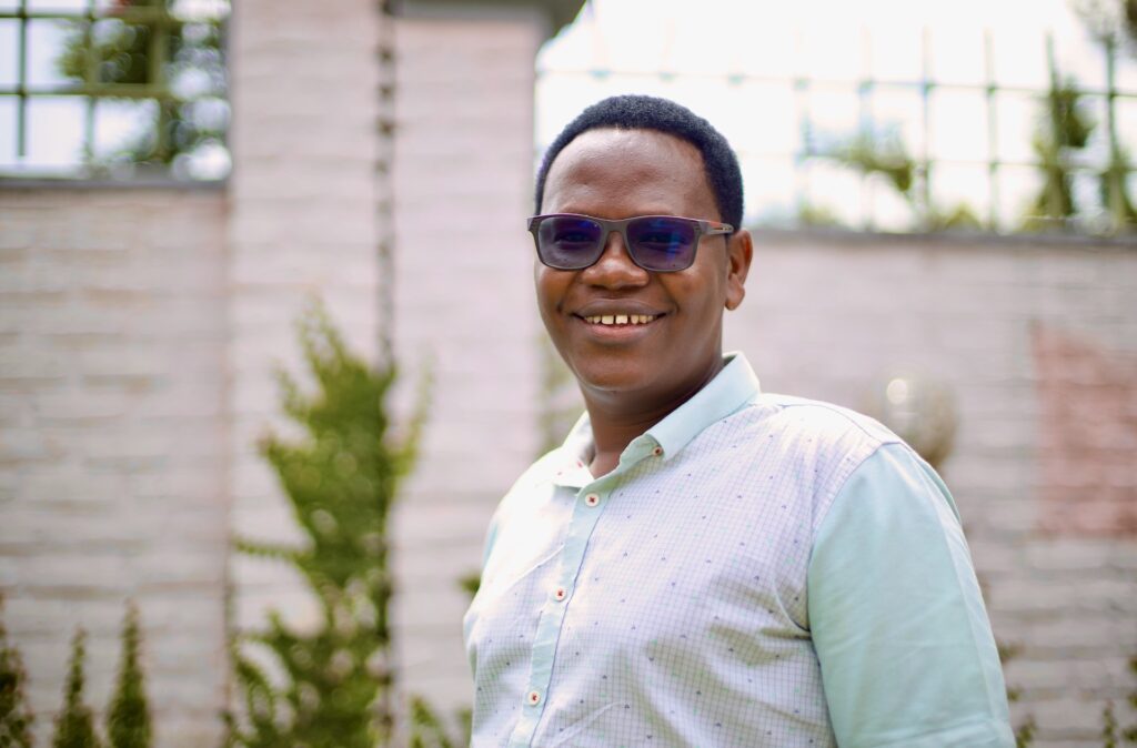 Portrait shot of Jean-Pierre wearing sunglasses, a light blue shirt in Kigali.