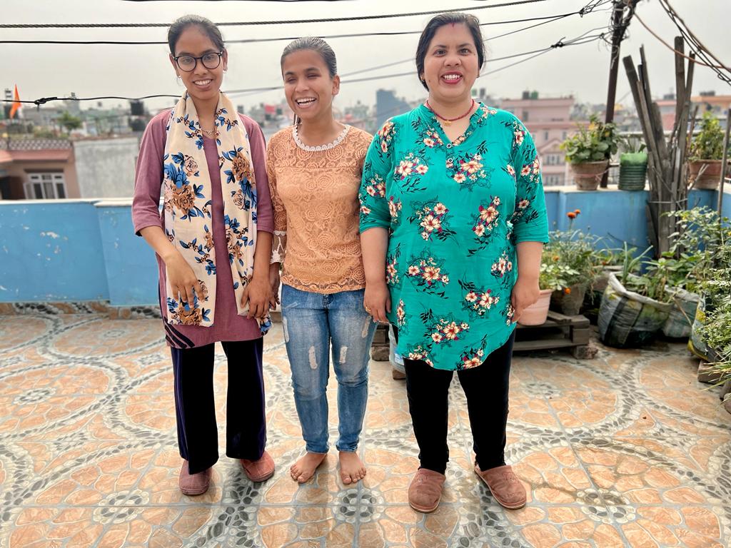 Three smiling women staff members of DRF/DRAF grantee, Pahichan, stand on a terrace in Kathmandu, Nepal.
