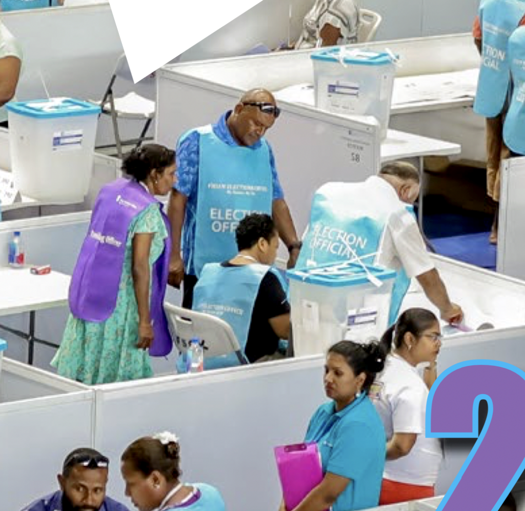 Election officers wearing purple and blue vests at voting booth in Fiji